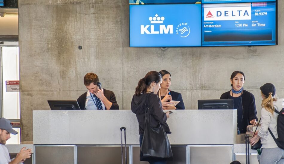 Een vrouw staat met haar bagage bij de balie van de KLM.