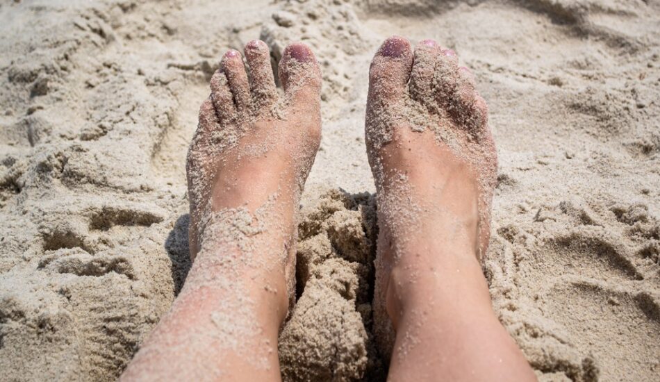 Voeten met zand erop op het strand
